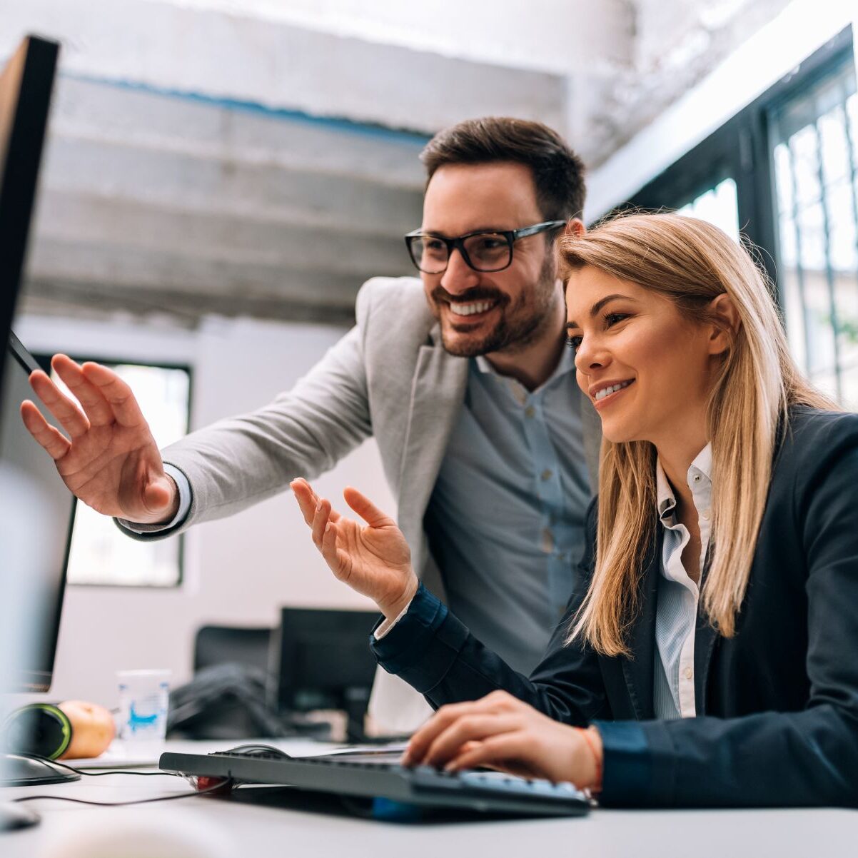 Working together on project. Two young business colleagues worki Working together on project. Two young business colleagues working on computer